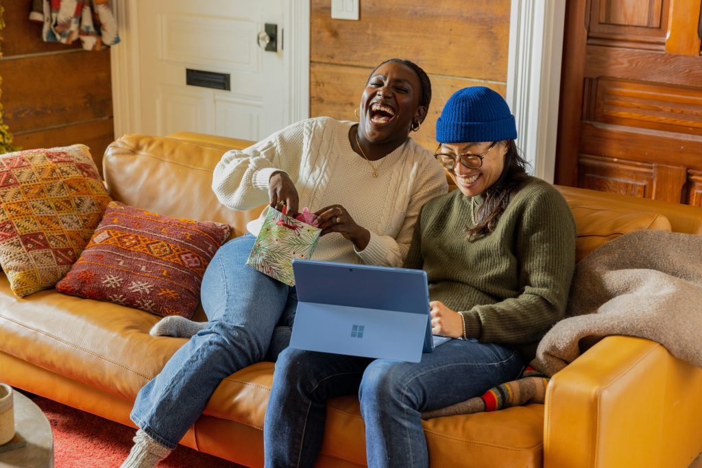 Two women laughing together while sitting on the sofa