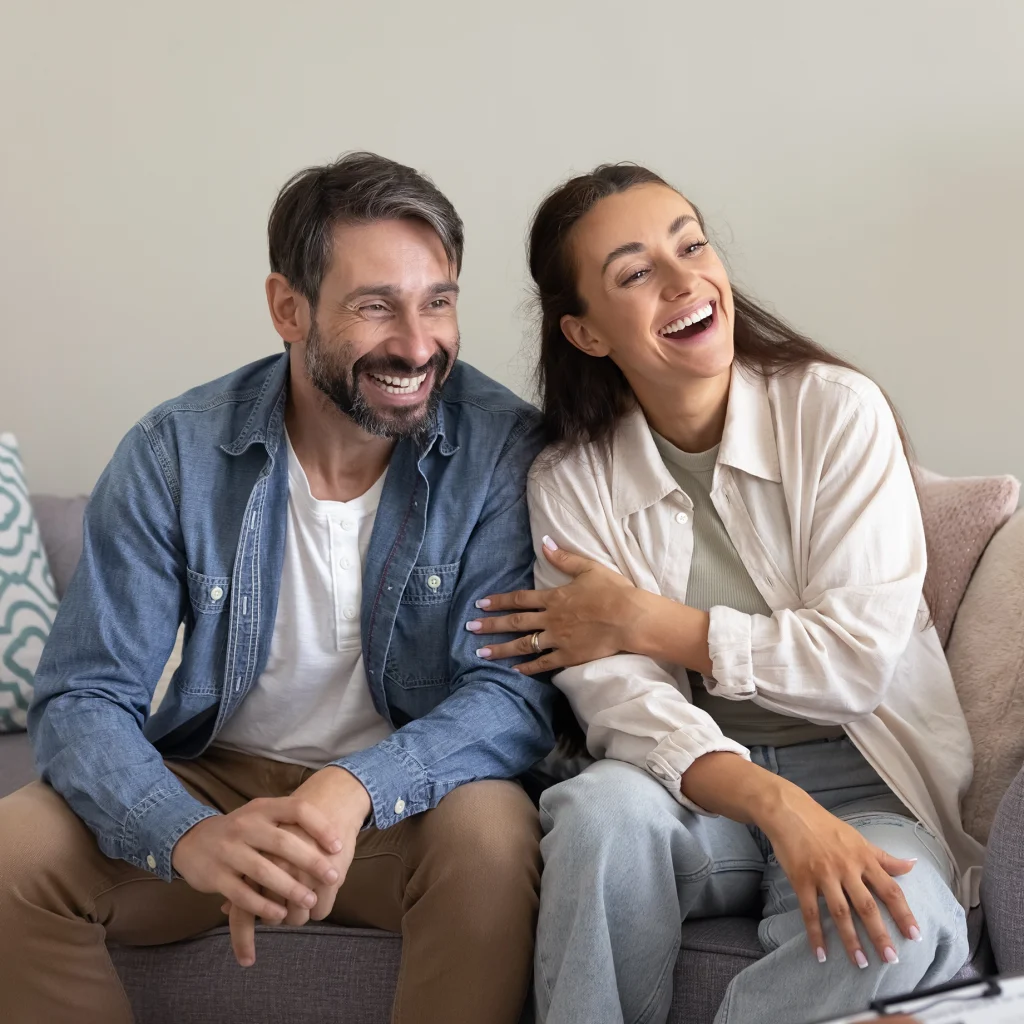 A couple laughing together on a sofa